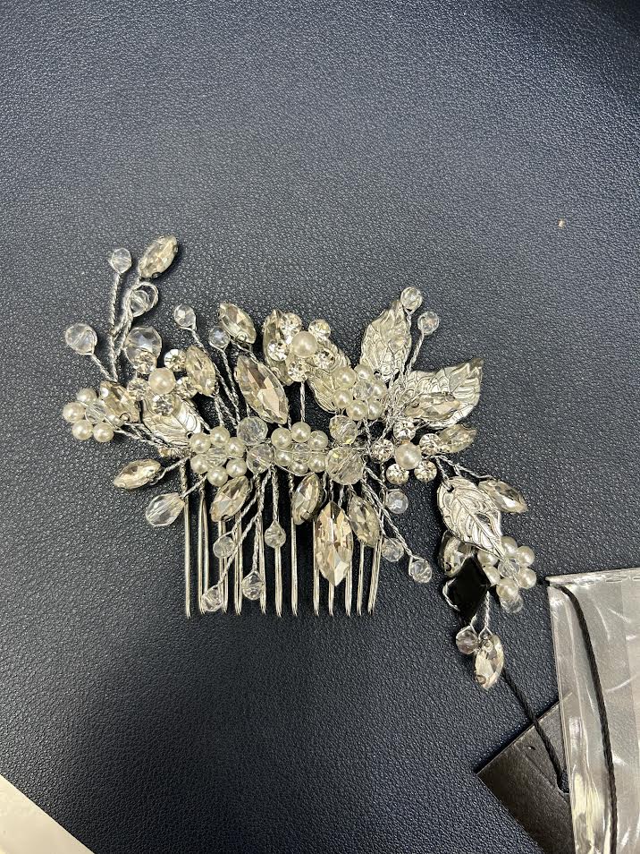Silver hair comb with decorative leaves and crystals on a dark surface