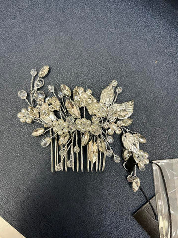 Silver hair comb with decorative leaves and crystals on a dark surface
