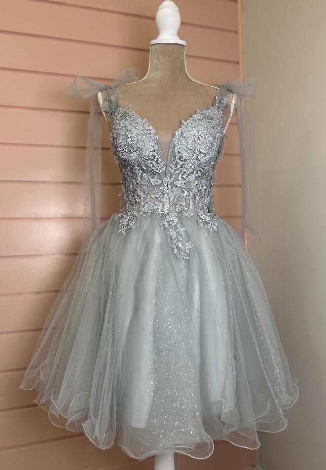 Silver beaded dress on a mannequin against a wooden panel background